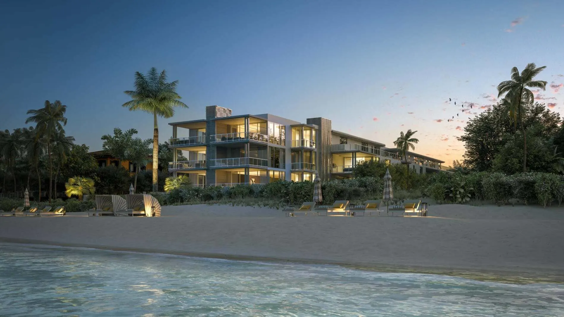 Modern beachfront condo at 1625 Ocean in Delray Beach with glowing interiors, and palm trees, along the sandy shoreline.